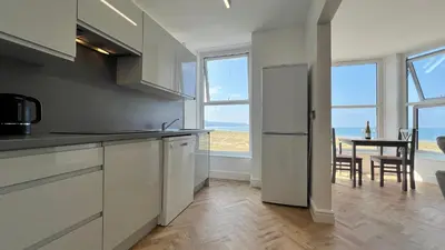 a kitchen with white cabinets and a table with chairs at Barmouth Beach Front Apartments in Barmouth