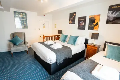 a hotel room with two beds and a chair at Without A Paddle Hotel in Llangollen