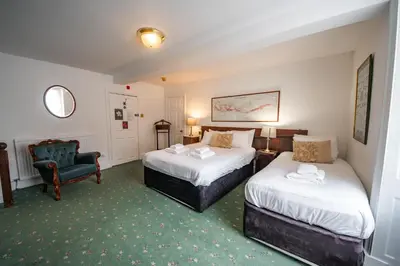 a hotel room with two beds and a chair at Without A Paddle Hotel in Llangollen