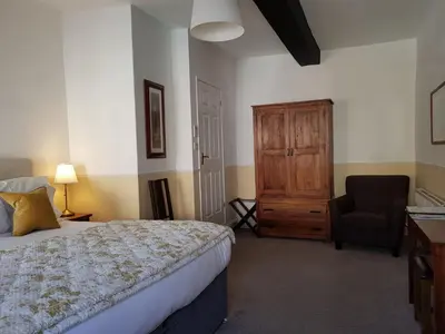a bedroom with a bed and a chair at Ty Helyg Guest House in Brecon