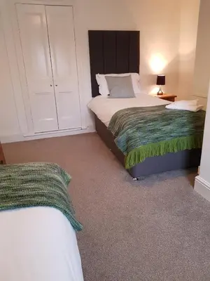 a bedroom with two beds and a dresser and a bed at Ty Helyg Guest House in Brecon