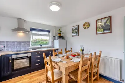 a kitchen with a wooden table with chairs and a dining room at 3 Bed in Llanrhystud oc-m28913 in Llanrhystyd