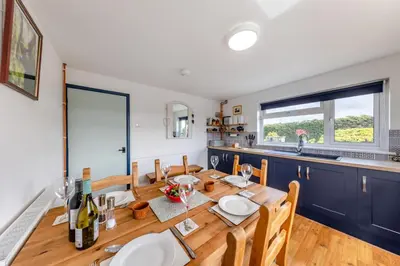 a dining room with a table and chairs and a kitchen at 3 Bed in Llanrhystud oc-m28913 in Llanrhystyd