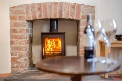 a brick fireplace with a table with a bottle of wine at 3 Bed in Llanrhystud oc-m28913 in Llanrhystyd