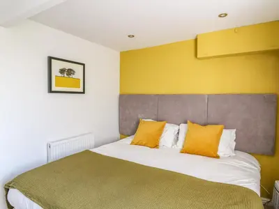 a bedroom with a large bed with yellow walls at 1 Gibraltar Terrace in Aberdyfi