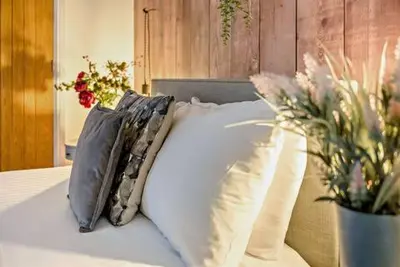 a bed with pillows and a vase of flowers on it at Beautiful Town Centre Apartment 110 Square Metre With Parking WEEKLY and MONTHLY Reduced Rates in Shrewsbury