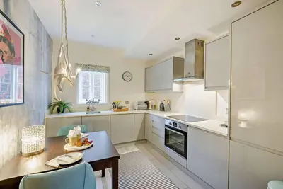 a kitchen with white cabinets and a wooden table at Beautiful Town Centre Apartment 110 Square Metre With Parking WEEKLY and MONTHLY Reduced Rates in Shrewsbury