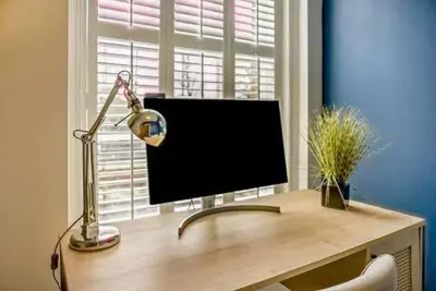 a computer monitor sitting on a desk in front of a window at Beautiful Town Centre Apartment 110 Square Metre With Parking WEEKLY and MONTHLY Reduced Rates in Shrewsbury