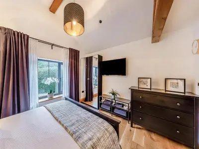 a bedroom with a bed and a dresser and a television at The Oaks in Llangollen