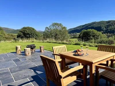 a wooden table with two glasses of wine on a patio at Y Fedwen in Llanwddyn