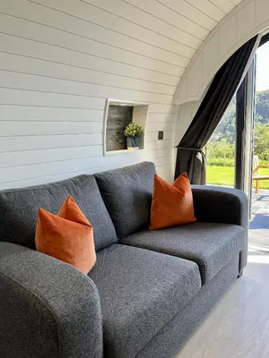 a gray couch with orange pillows in a living room at Y Fedwen in Llanwddyn