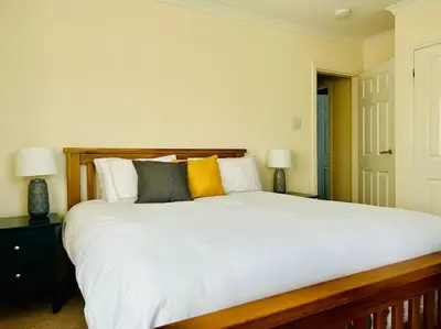 a bedroom with a large white bed with two lamps at Snowdonia coastal getaway ideal for groups up to 6 in Llwyngwril