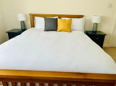 a large white bed with two night stands with two lamps at Snowdonia coastal getaway ideal for groups up to 6 in Llwyngwril