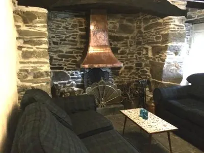 a living room with a couch and a stone fireplace at Mellow Mountain Eco Retreat Wales Hot-Tub Sauna in Glyn-Ceiriog