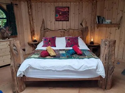 a bedroom with a wooden bed with pillows on it at Magical Offgrid Roundhouse in Eryri in Machynlleth