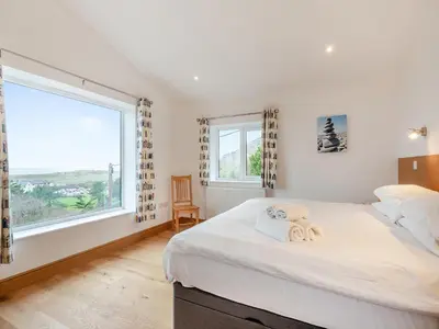 a bedroom with a large window and a bed with towels at Bodwennol in Aberdyfi