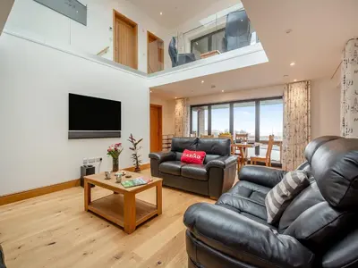 a living room with black leather furniture and a flat screen tv at Bodwennol in Aberdyfi