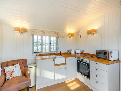 a kitchen with white cabinets and a chair and a microwave at Sunflower - Uk42360 in Saint Harmon