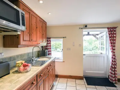 a kitchen with wooden cabinets and a sink and a window at The Old Coach House -Uk41272 in Great Hanwood