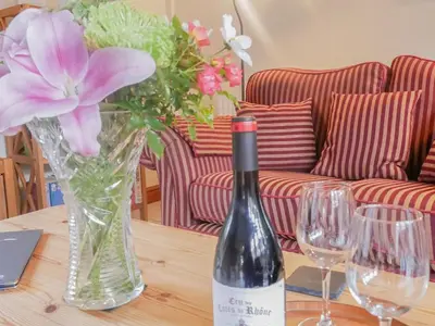 a bottle of wine and a vase with flowers on a table at The Old Coach House -Uk41272 in Great Hanwood