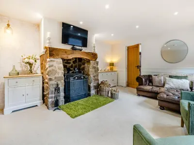 a living room with a stone fireplace with a tv above it at The Lodge Spa - Uk47837 in Church Pulverbatch