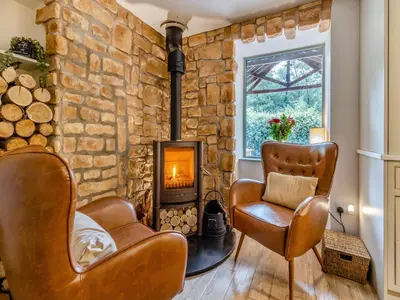 a living room with two chairs and a stone fireplace at The Lodge Spa - Uk47837 in Church Pulverbatch