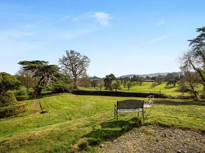 a bench sitting in a field of grass at Apartment At Llanerchydol Hall in Welshpool
