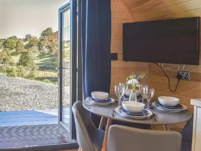 a table with chairs and a television in a room with a window at Glampio Trysor Merddwr-Ukc5826 in Llangwm