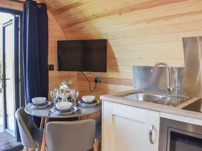 a kitchen with a table with a sink and a tv at Glampio Trysor Merddwr-Ukc5826 in Llangwm