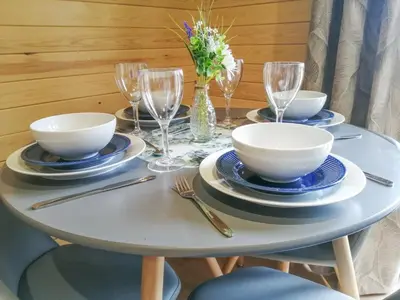 a table with plates and bowls and wine glasses at Glampio Tryso Garth-Ukc5827 in Llangwm