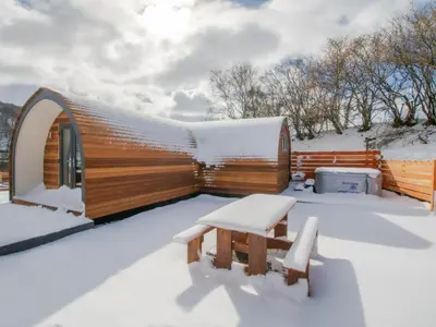 a round wooden house in the snow with two benches at Glampio Tryso Garth-Ukc5827 in Llangwm
