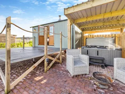 a patio with a grill and chairs on a deck at Mayflower - Uk42359 in Saint Harmon