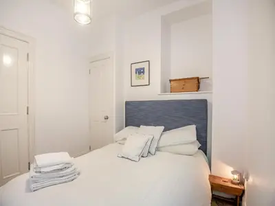 a white bedroom with a large white bed with white pillows at Apartment 2 in Aberdyfi