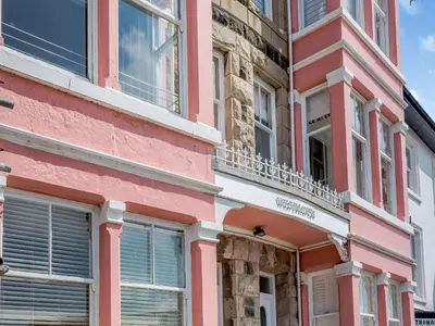 a pink building with windows and a balcony at Apartment 2 in Aberdyfi