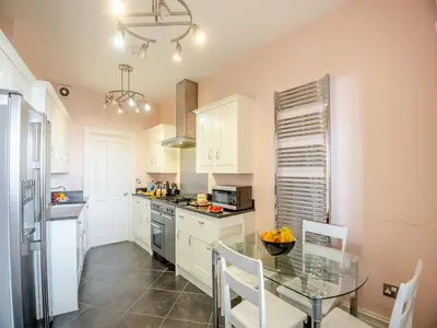 a kitchen with white cabinets and a glass table at Apartment 2 in Aberdyfi