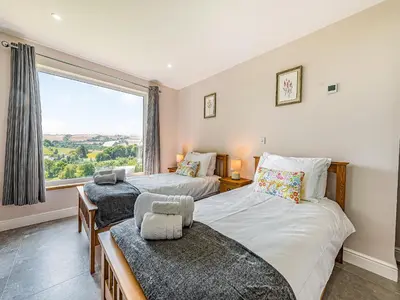 two beds in a room with a large window at Llwynblyfyn in Llansawel