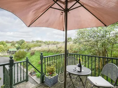 a table and chairs with an umbrella on a balcony at The Corn House - Cottage in Great Hanwood
