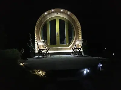two chairs sitting in front of a window at night at Ty Barcud Glamping Pod in Aberystwyth