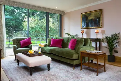 a living room with a green couch and pink pillows at Bryngwilla Gate Lodge in Oswestry