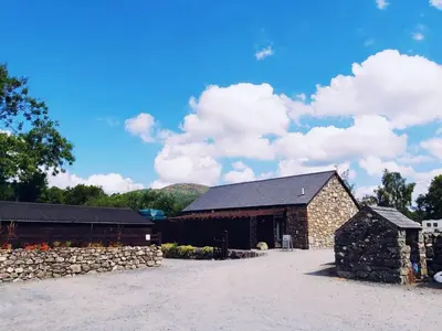 a barn with a stone wall next to a building at Bunkhouse Accommodation in the Heart of Snowdonia in Dolgellau