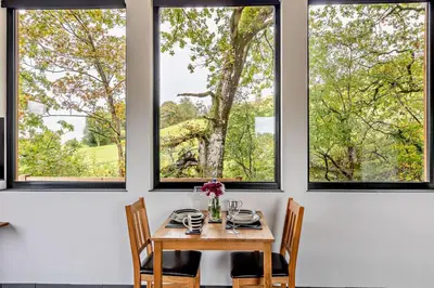a dining room with a table and three windows at 1 Bed in Llanerfyl oc-d30168 in Llanfair Caereinion