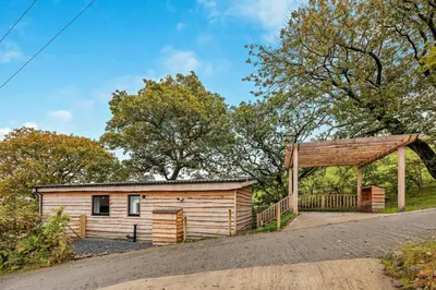 a wooden cabin with a wooden pavilion next to a road at 1 Bed in Llanerfyl oc-d30168 in Llanfair Caereinion