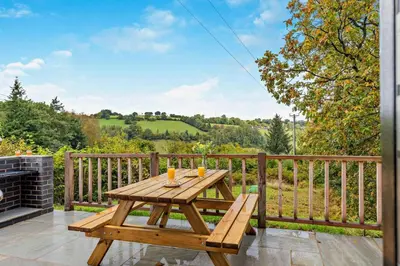 a wooden picnic table on a deck with a fireplace at 1 Bed in Llanerfyl oc-d30168 in Llanfair Caereinion
