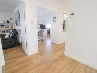 a living room with a black couch and a wooden floor at The Gables in Tywyn