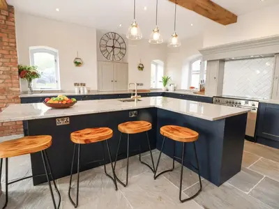 a kitchen with a blue island with stools at Tanat House in Oswestry
