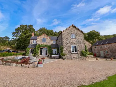 a large stone house with a gravel driveway at Tanat House in Oswestry