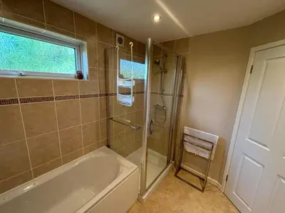 a bathroom with a tub and a shower with a window at Ash Lodge in Craven Arms