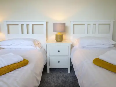 a bedroom with two beds and a night stand with a lamp at The Wardens House in Newtown