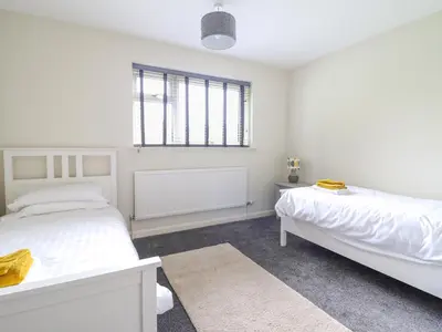 a white bedroom with two beds and a window at The Wardens House in Newtown