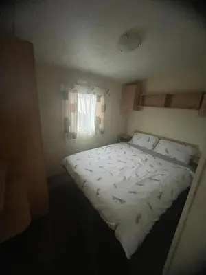 a bedroom with a large bed with white sheets and a window at Gorgeous Sea Viev 3 Bedroom Delta Bromley Deluxe in Aberystwyth